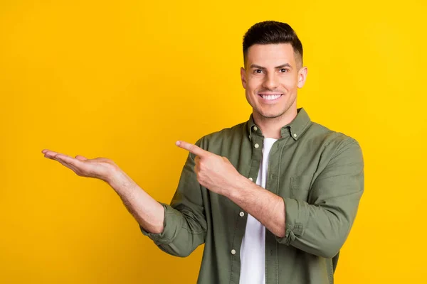 Genç adamın fotoğrafı mutlu bir gülümseme işaret parmağı reklamı sarı arkaplanda izole edilmiş. — Stok fotoğraf