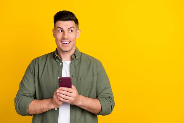 Foto retrato homem sorrindo olhando copyspace digitando mensagem no smartphone isolado cor amarela brilhante fundo — Fotografia de Stock