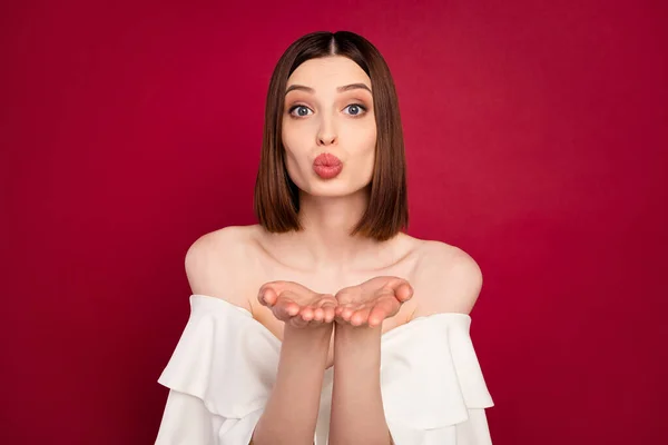 Foto de flirty marrón peinado joven dama golpe beso desgaste blanco desnudo hombros blusa aislado en color rojo fondo — Foto de Stock