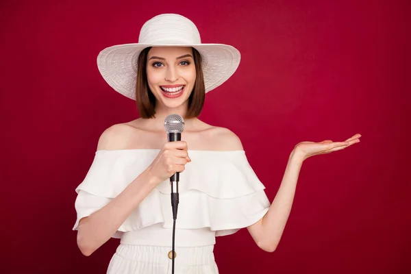 Foto di giovane donna attraente felice sorriso positivo cantare mic karaoke tenere mano prodcut annunci isolati su sfondo di colore rosso — Foto Stock