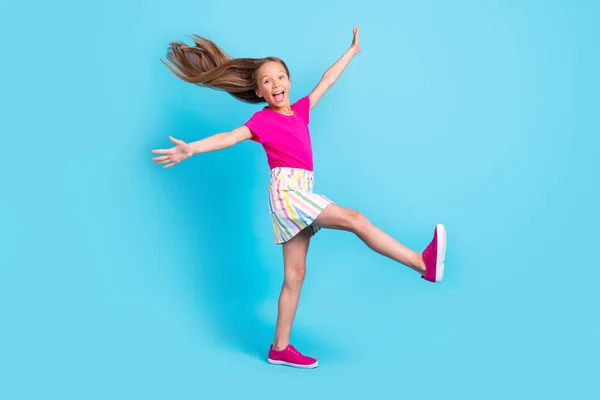 Foto em tamanho completo de alegre jovem surpreso menina feliz levantar as mãos perna voar cabelo isolado no fundo de cor azul — Fotografia de Stock