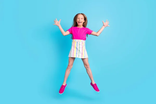Foto de comprimento total de alegre alegre surpreendido menina pequena saltar para cima levantar as mãos isoladas no fundo de cor azul — Fotografia de Stock