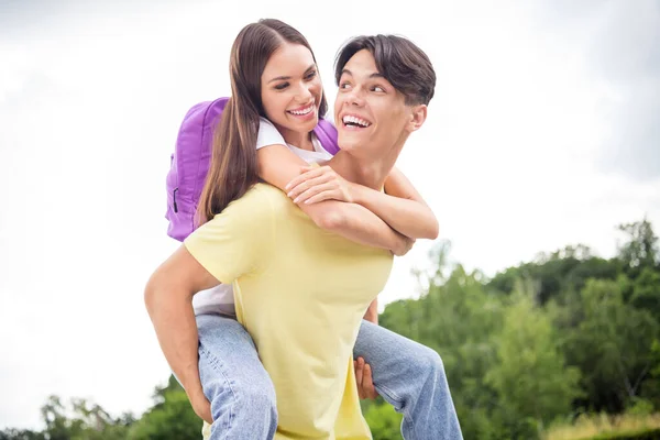 Foto de dos hermanitos juguetones llevando ropa casual mochila caminando de vuelta sonriendo al aire libre campo — Foto de Stock