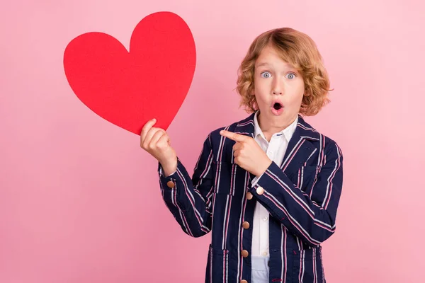 Foto do jovem menino pequeno ponto surpreso dedo ouvir sentimentos forma amor anúncios escolher isolado sobre fundo cor pastel — Fotografia de Stock