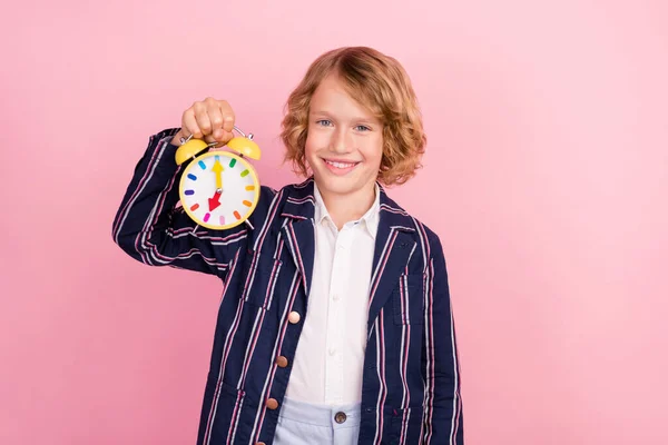 Foto do menino da escola feliz sorriso positivo segurar relógio temporizador lição estudo isolado sobre cor rosa fundo — Fotografia de Stock