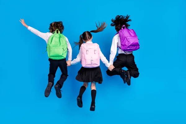 Foto de funky divertido colegiales formalwear mochilas sonriendo saltando brazos de alta celebración aislado de color azul de fondo — Foto de Stock