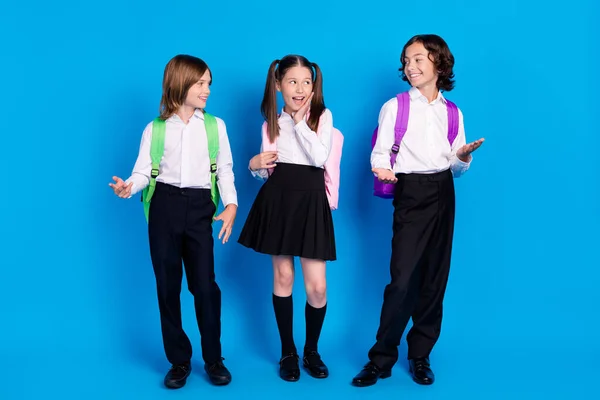 Foto de encantadoras mochilas escolares emocionadas formalwear sonriendo hablando mirando el uno al otro aislado fondo de color azul — Foto de Stock