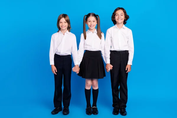 Photo of charming sweet schoolchildren wear uniform holding arms smiling isolated blue color background — Stock Photo, Image