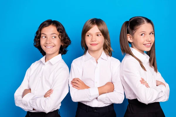 Foto de adorables escolares brillantes usan uniformes brazos sonrientes cruzados aislados color azul fondo — Foto de Stock