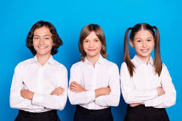 Fotografie veselých sebevědomé školáci zkřížené ruce nosit školní uniformu izolované modré barvy pozadí — Stock fotografie