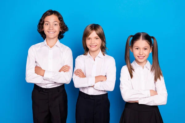 Fotografie sladké rozkošné školáci nosí uniformu usmívající se paže křížené izolované modré barvy pozadí — Stock fotografie