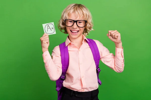 Foto de joven alegre positivo niño feliz agarre pegatina de papel de la mano buena marca ganar aislado en el fondo de color verde —  Fotos de Stock