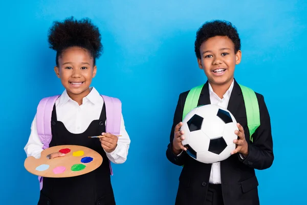 Foto van kleine donkere huid kinderen dragen formalwear uniform hold palet bal geïsoleerd op blauwe kleur achtergrond — Stockfoto