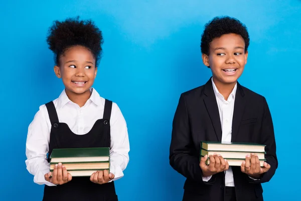 年轻的非洲裔美国好奇的孩子们互相望着对方，抱着书本，带着蓝色背景的微笑 — 图库照片