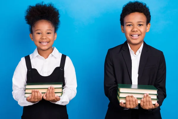 Foto de pele escura positiva feliz crianças alunos segurar materiais livros sorriso isolado no fundo de cor azul — Fotografia de Stock