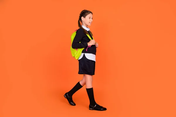 Full size photo of happy young dreamy girl look go empty space school wear bag isolated on orange color background — Stock Photo, Image