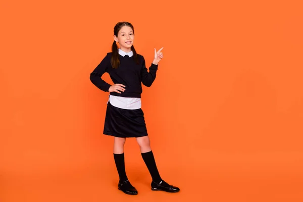 Foto de tamaño completo de la pequeña colegiala feliz dedo dedo vacío espacio venta temporada sonrisa aislada sobre fondo de color naranja —  Fotos de Stock