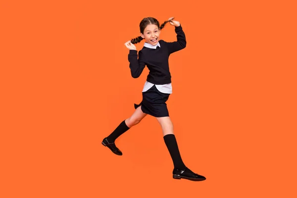 Full size profil boční fotografie mladé dívky šťastný pozitivní úsměv bavit hravý skok izolované přes oranžové barvy pozadí — Stock fotografie