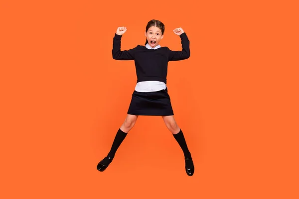 In voller Länge Foto von jungen Mädchen glücklich positives Lächeln feiern Sieg Erfolg Fäuste Hände springen isoliert über orange Farbhintergrund — Stockfoto