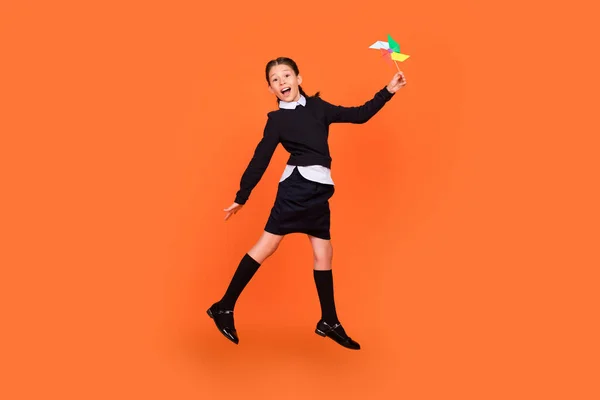 Full length body size view of pretty carefree cheery preteen girl jumping playing paper fan isolated over bright orange color background — Stock Photo, Image