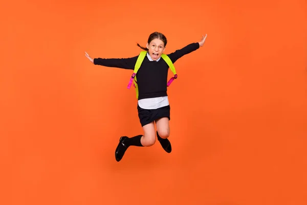 Foto de una estudiante descuidada colegiala salto loco vuelo desgaste uniforme mochila aislado color naranja fondo —  Fotos de Stock