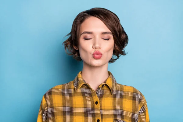Foto van aanhankelijk meisje stuur lucht kus sluit ogen dragen geruite geruit shirt geïsoleerde blauwe kleur achtergrond — Stockfoto