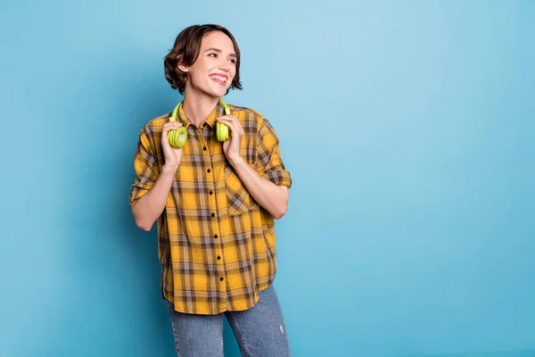 Foto de senhora despreocupada inspirada olhar espaço vazio usar fones de ouvido camisa xadrez isolado azul cor fundo — Fotografia de Stock