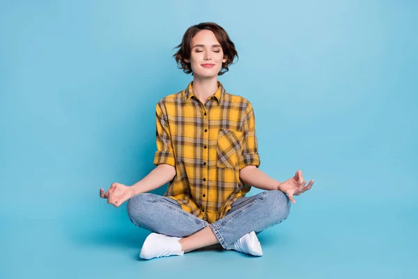 Foto da senhora concentrada focada sentar chão meditar fechar os olhos usar camisa xadrez isolado fundo cor azul — Fotografia de Stock