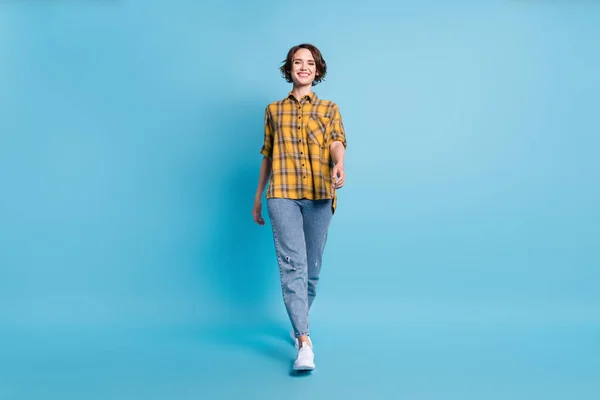 Çekici, pozitif kadın yürüyüşünün fotoğrafı. Kareli gömlek, kot ayakkabılar, izole edilmiş mavi arka plan. — Stok fotoğraf