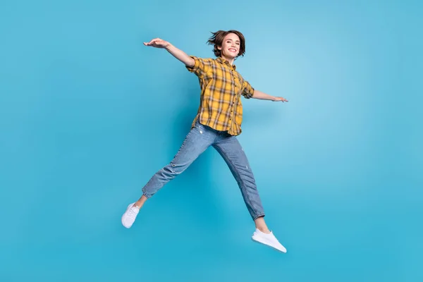 Photo of lovely inspired lady jump fly posing plane wear plaid shirt jeans footwear isolated blue color background — Stock Photo, Image