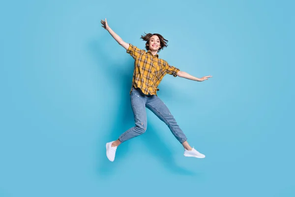 Heyecanlı bayan atlayışı fotoğrafı uçak pozu hayal et ekose gömlek pantolon giy izole edilmiş mavi arka plan — Stok fotoğraf