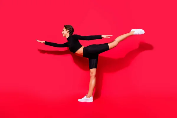 Full length body size profile side view of attractive cheerful girl stretching keeping balance isolated over bright red color background — Stock Photo, Image