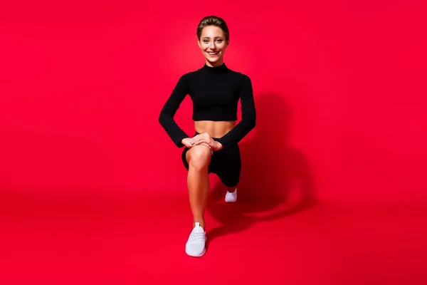 Retrato de chica fuerte atractiva alegre resistente haciendo sit ups crossfit aislado sobre fondo de color rojo brillante —  Fotos de Stock