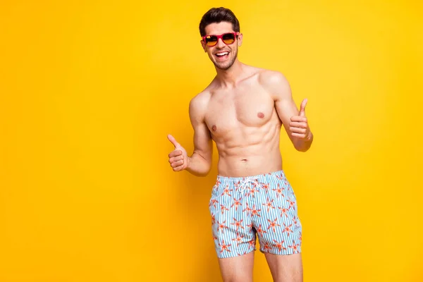 Foto de divertido atractivo joven torso desnudo sonriendo mostrando pulgares hacia arriba aislado color amarillo fondo — Foto de Stock