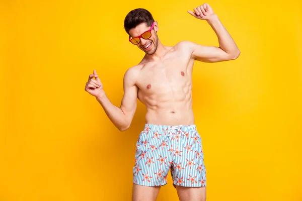 Portrait of atraktive shirtless cheerful guy dancing having fun isolated over bright yellow color background — Stok Foto