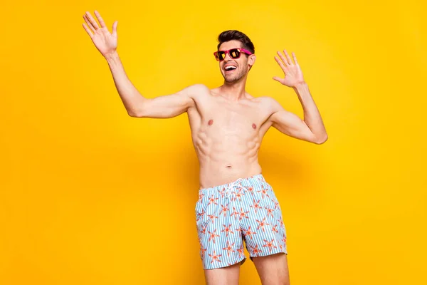 Foto de encantador lindo joven desnudo torso desgaste gafas oscuras bailando sonriente aislado color amarillo fondo — Foto de Stock