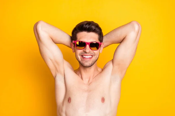Foto di attraente dolce giovane uomo nudo busto scuro braccia occhiali dietro la testa sorridente isolato colore giallo sfondo — Foto Stock