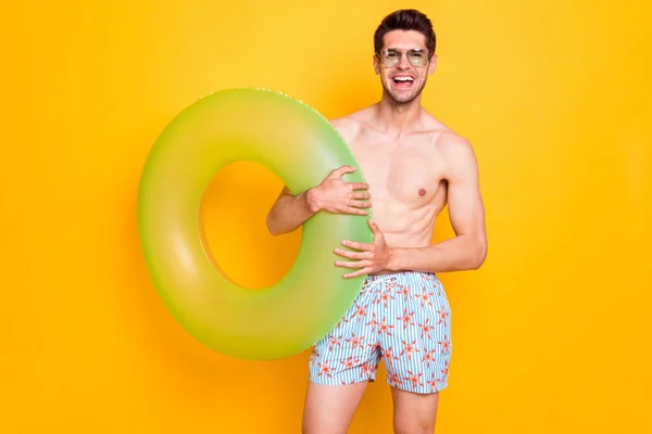 Foto de brunet impresionado chico milenario mantenga boya desgaste gafas pantalones cortos aislados sobre fondo de color amarillo — Foto de Stock