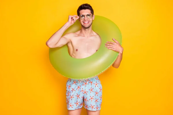 Foto di divertente dolce giovane uomo nudo busto indossare occhiali scuri camminare tenendo cerchio d'acqua sorridente isolato colore giallo sfondo — Foto Stock