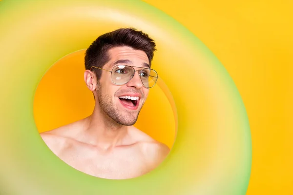 Foto di affascinante impressionato uomo nudo busto occhiali scuri cercando all'interno cerchio gonfiabile spazio vuoto isolato colore giallo sfondo — Foto Stock