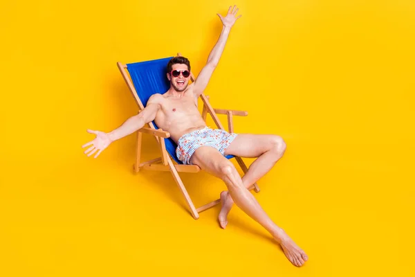Lunghezza completa dimensione del corpo vista di attraente ragazzo allegro seduto sulla sedia avendo divertimento week-end resort isolato su sfondo di colore giallo brillante — Foto Stock