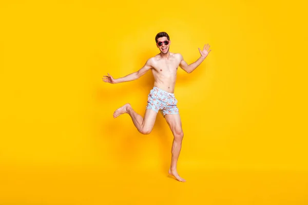 Photo of pretty impressed young guy shirtless wear dark glasses smiling dancing isolated yellow color background — Stock Photo, Image