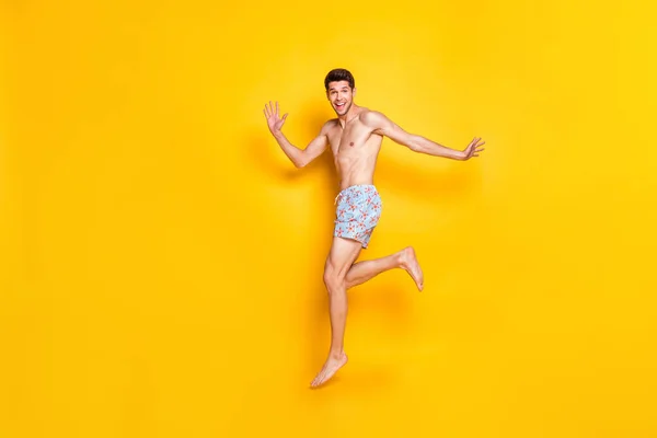 Teljes hosszúságú fotó vicces brunet fiatal férfi ugrás viselet rövidnadrág elszigetelt sárga háttér — Stock Fotó