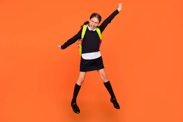 Full length body size view of pretty lucky cheerful schoolgirl jumping rejoicing having fun isolated over bright orange color background — Stock Photo, Image