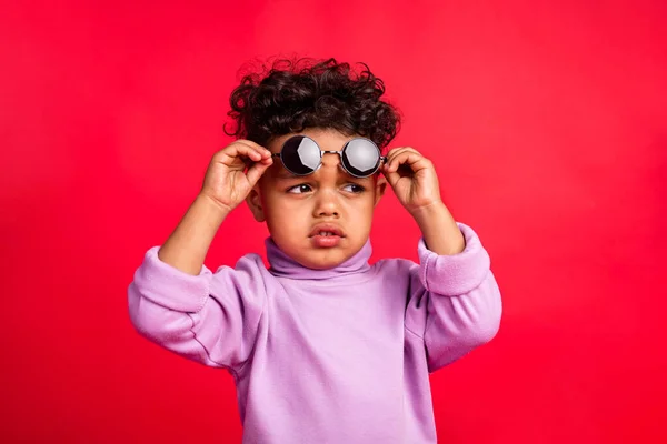 Retrato de atractivo sospechoso funky niño tocando especificaciones buscando encontrar manera aislada sobre fondo de color rojo brillante —  Fotos de Stock