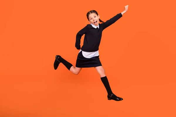 Foto de tamaño completo de alegre niña feliz saltar sorprendido escuela impactada aislado sobre fondo de color naranja — Foto de Stock