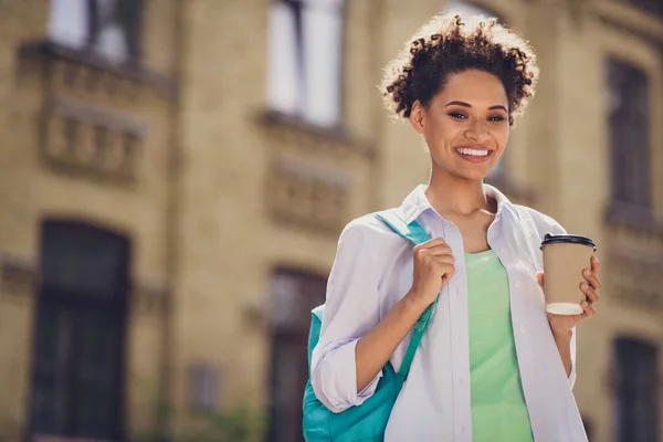 Foto van vrolijke gelukkig mooi afro-Amerikaanse vrouw houden koffie dragen rugzak onderwijs buiten — Stockfoto