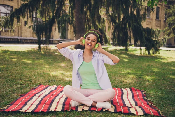 Foto de comprimento total de jovem afro mulher feliz sorriso positivo ouvir música fones de ouvido música parque natureza árvores — Fotografia de Stock