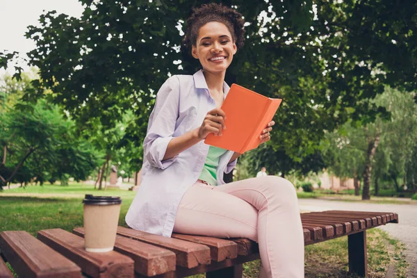 Foto de alegre mujer afro americana feliz buen humor sostener libro de la mano sonrisa al aire libre parque de la ciudad —  Fotos de Stock