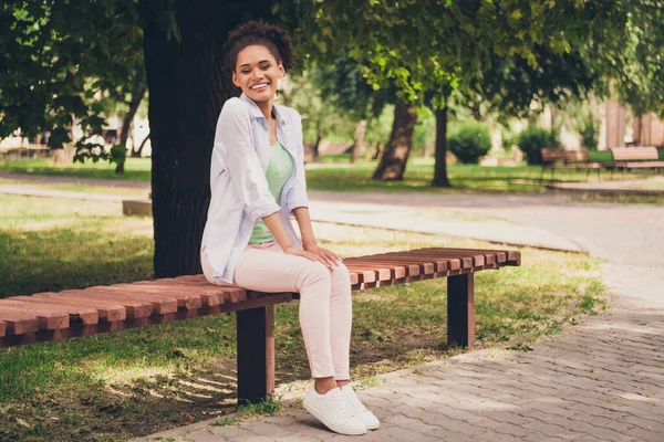 Corpo inteiro foto de alegre feliz positivo afro americano mulher sorriso sentar banco fim de semana fora ao ar livre parque — Fotografia de Stock